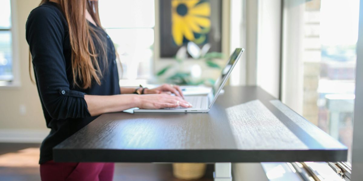 woman in black shirt sitting at the table using macbook